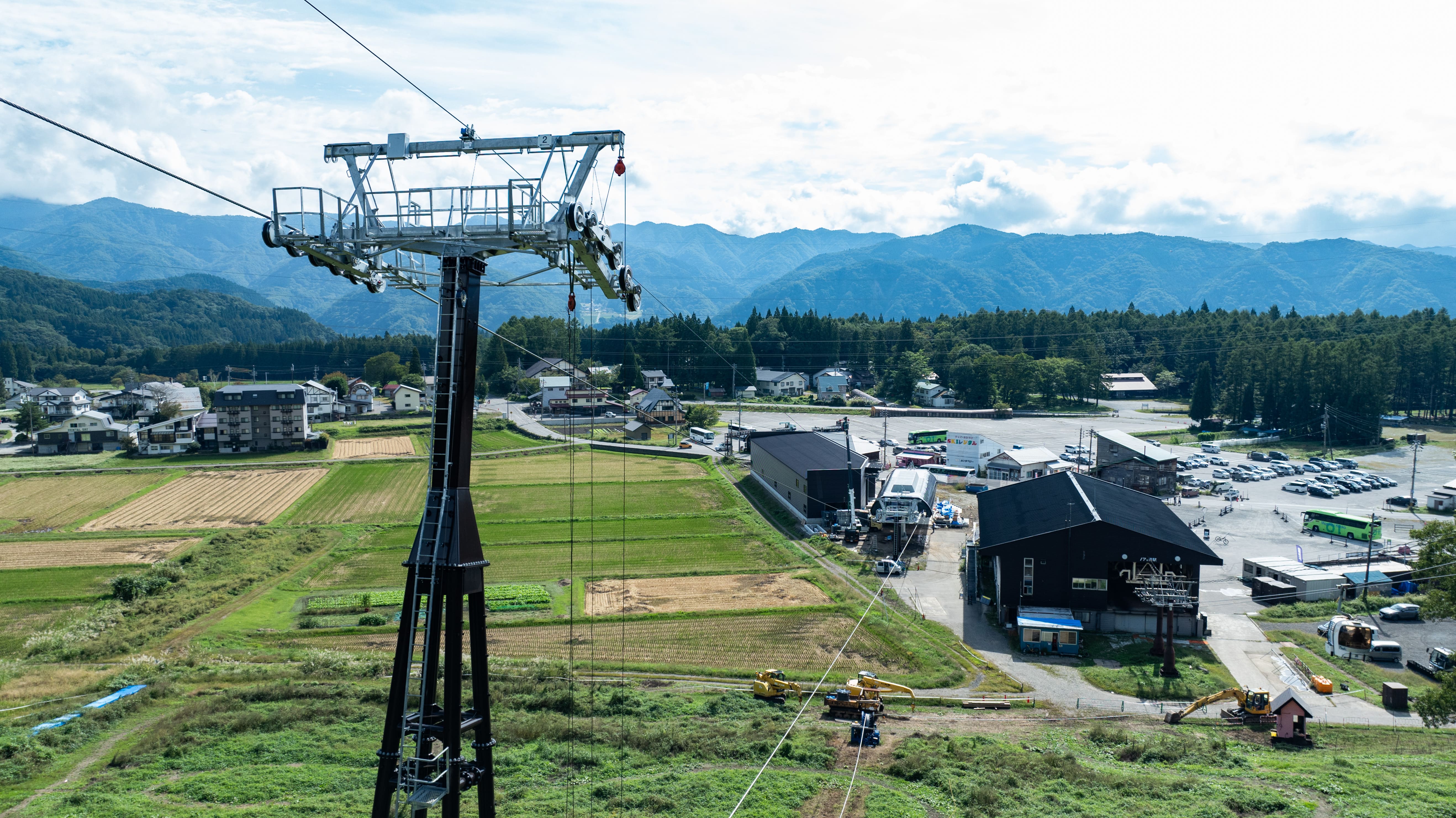 岩岳リゾート、持続可能な世界水準のマウンテンリゾートを目指し山麓ベースエリアの再開発を本格化のサブ画像2_建設中の新ゴンドラリフトの支柱と山麓駅（中央）（2024年9月25日撮影）